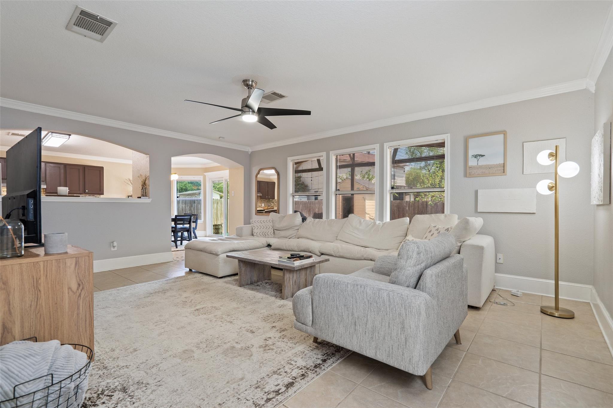 Furnished living room with a cream sectional, gray armchair, and windows facing a fenced yard.