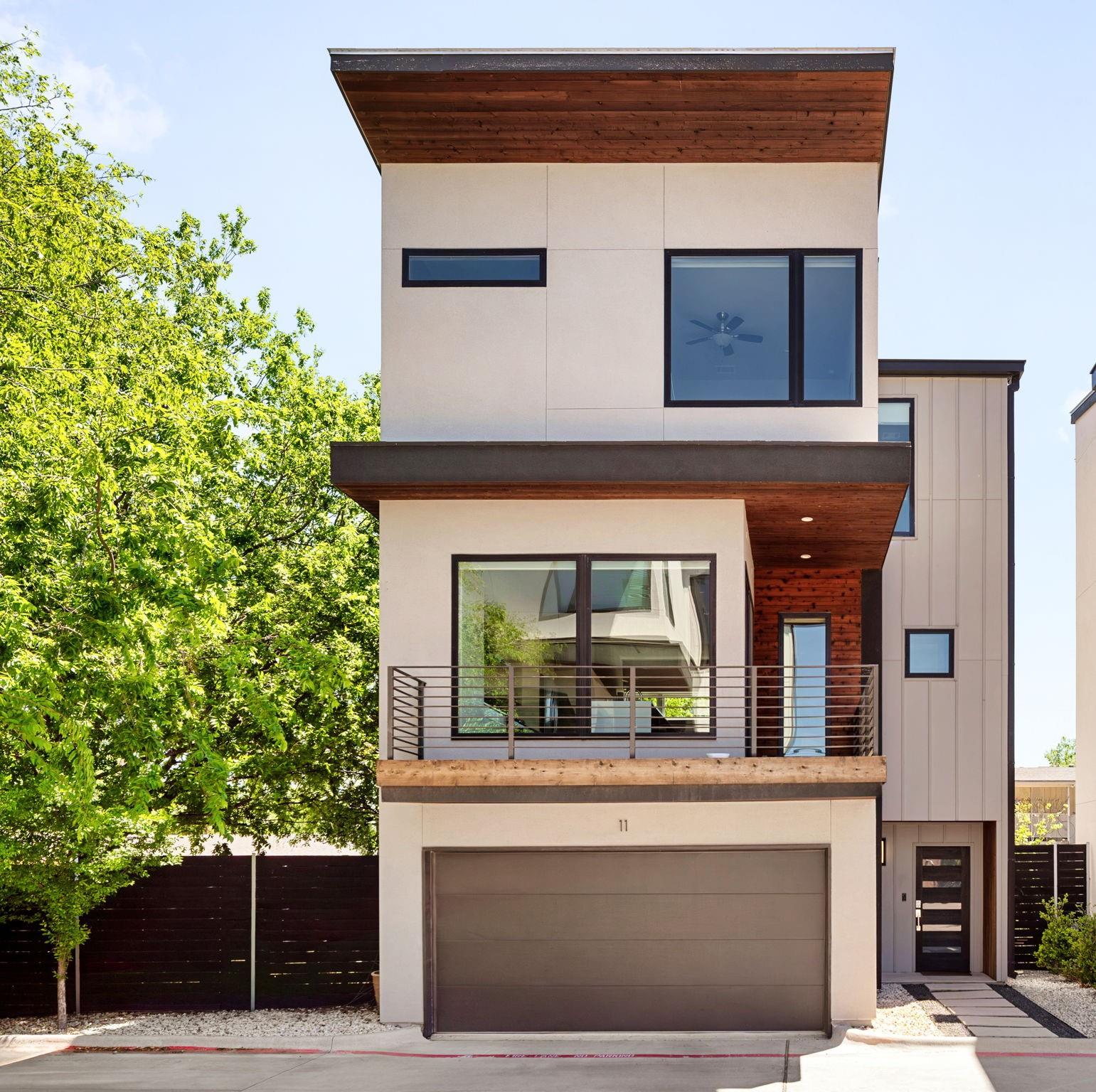 Modern multi-story home with wood soffits, a balcony, and an attached garage.