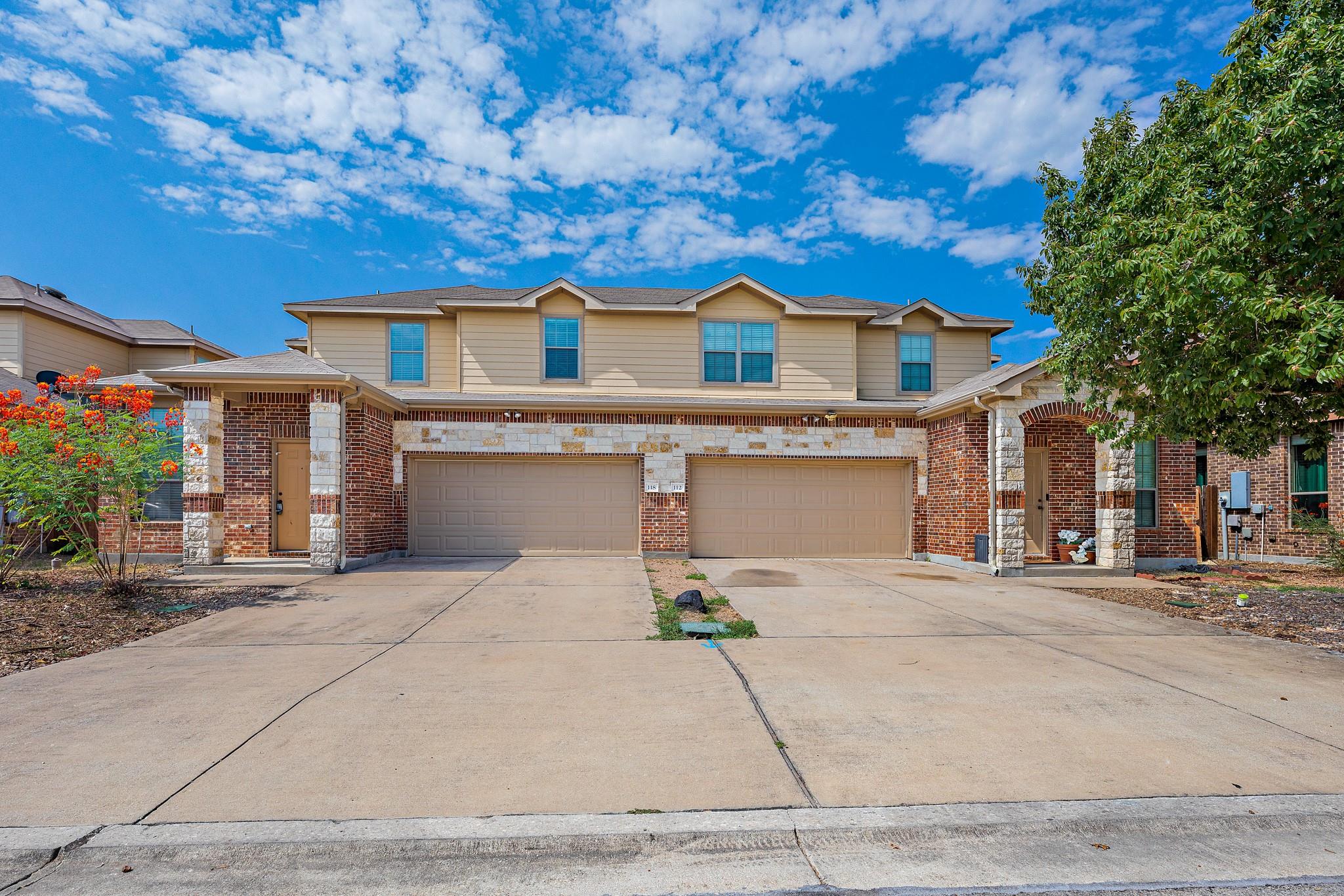 Two-story attached home with brick and stone accents, two garage doors, and a wide driveway.
