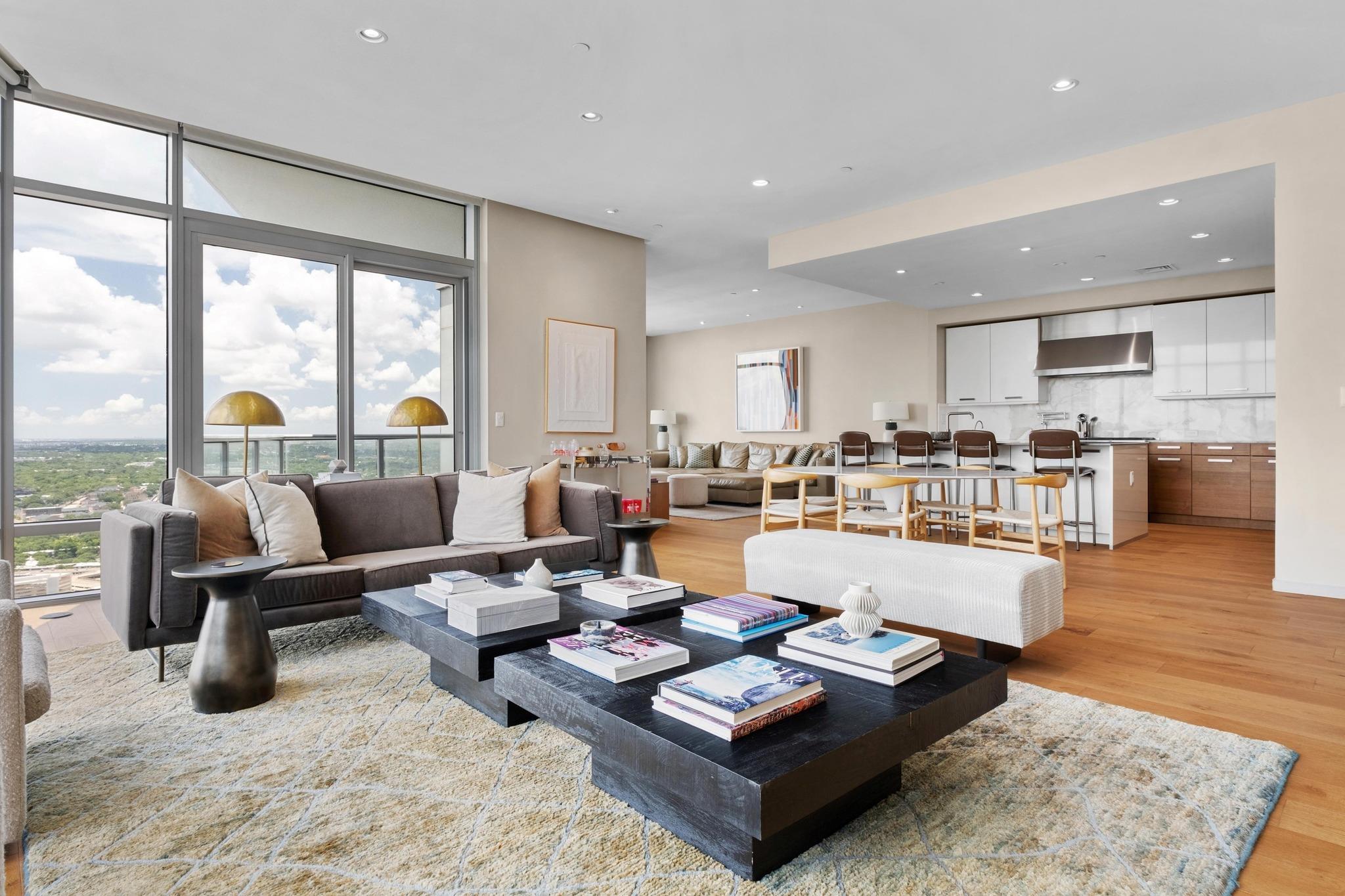 Open-plan living room and kitchen with floor-to-ceiling windows and a distant city view.