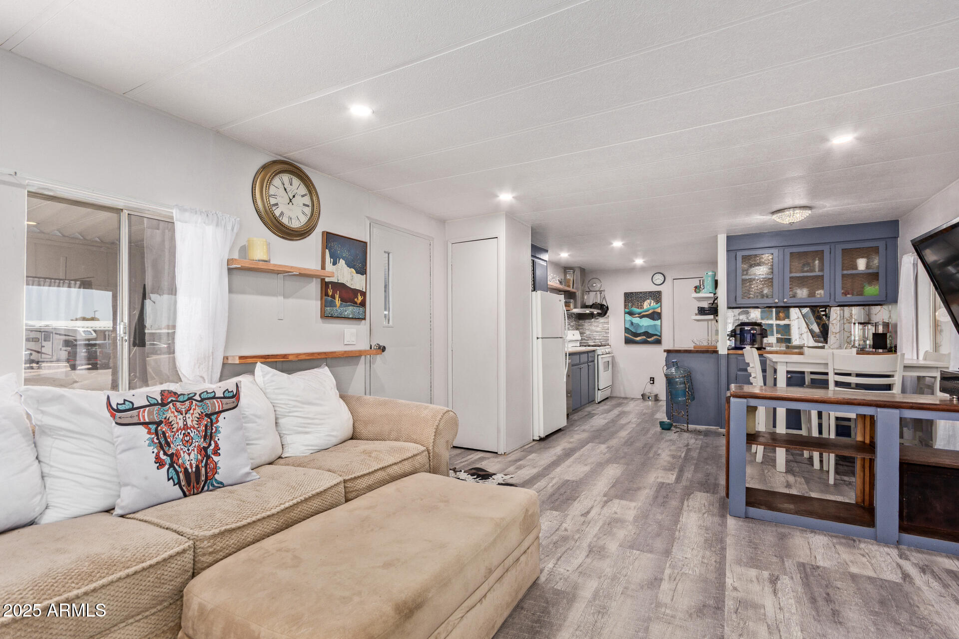 Open-plan living room and kitchen with a beige sectional and blue cabinetry.