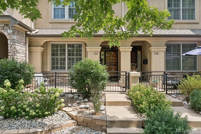 Beige multi-unit building with stone accents, landscaped front beds, and entrances numbered 132 and 134.