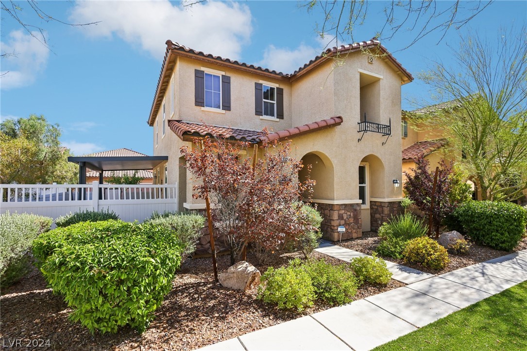 Two-story stucco home with tiled roof, arched entry, and landscaped front yard.