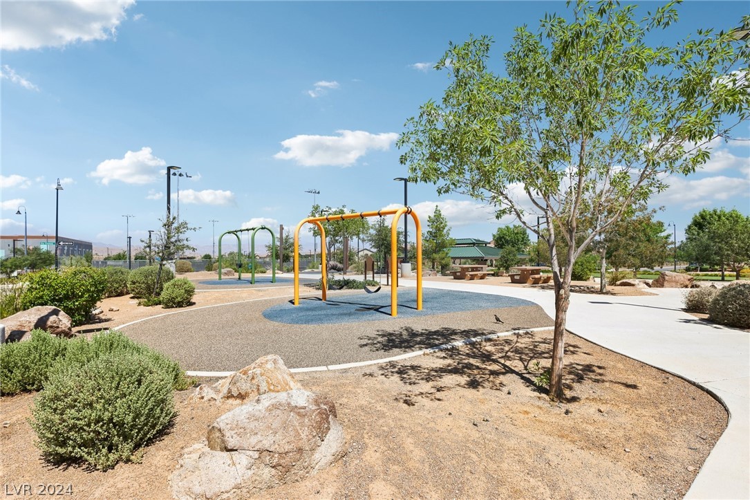 Community playground with colorful swings, shaded benches, and desert landscaping.