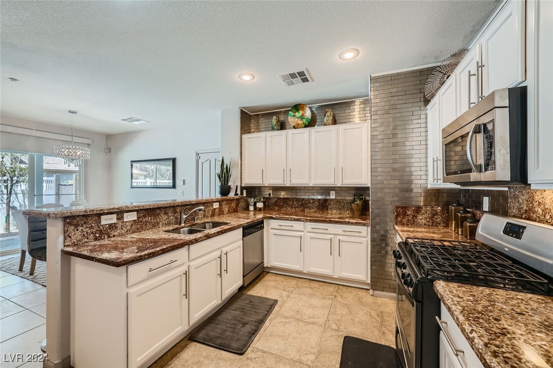 Kitchen with white cabinets, brown granite counters, and a black gas range.