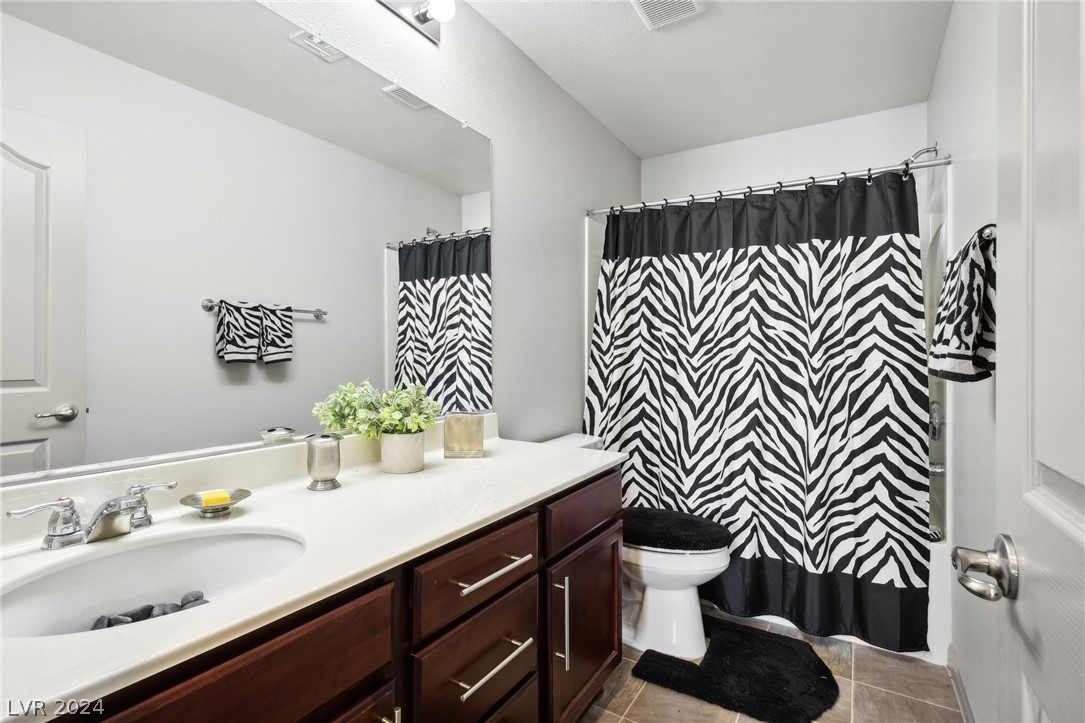 Bathroom with dark wood vanity, white countertop, and bold zebra-pattern shower curtain.