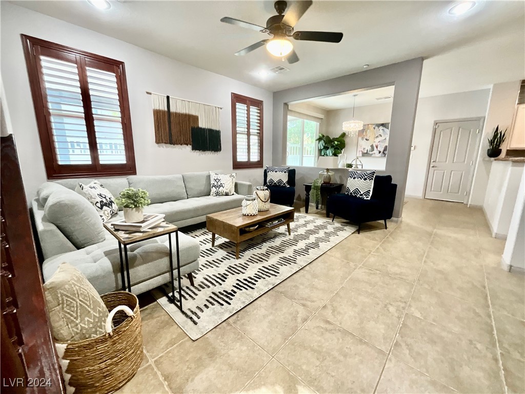 Living room with a gray sectional, dark armchairs, patterned rug, and plantation shutters.