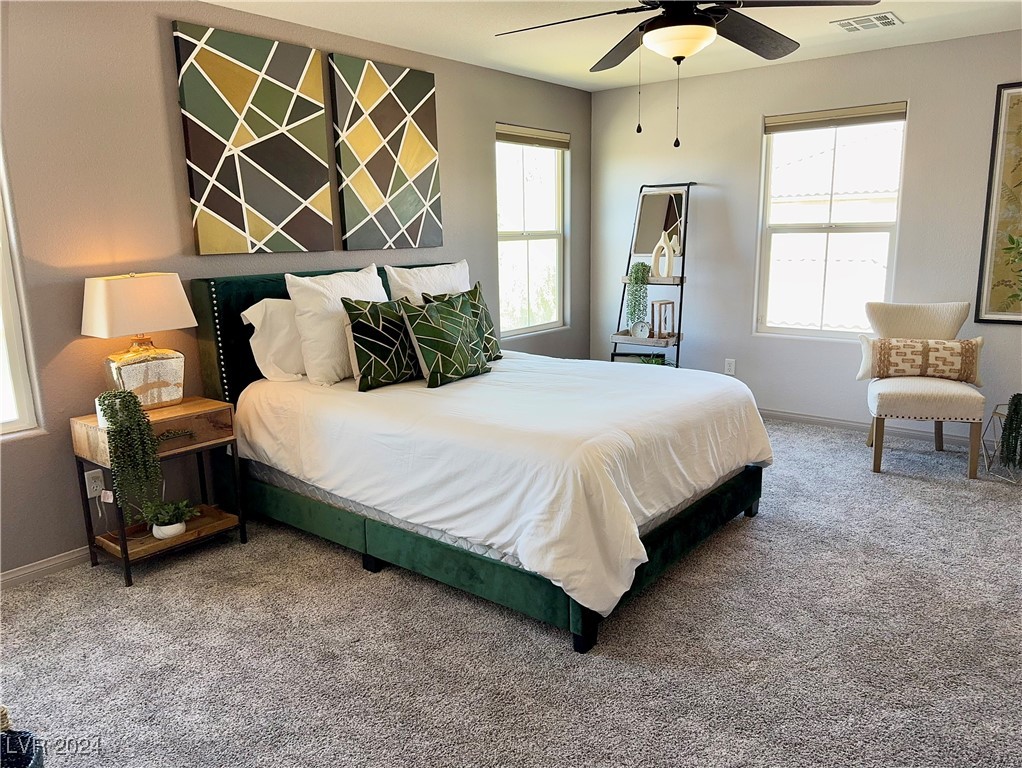 Staged bedroom with a white-covered bed, green frame, and bold geometric artwork.