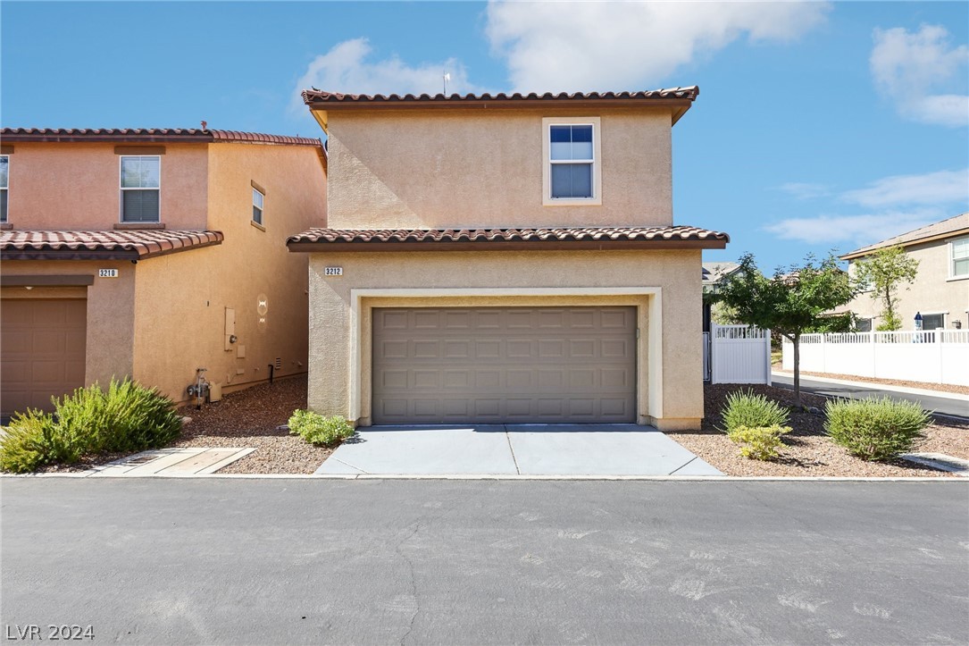 Two-story stucco home with a double garage, tiled roof and desert landscaping.