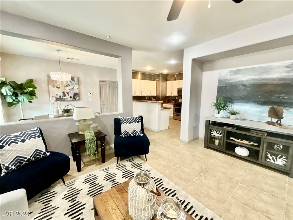 Living room opening to a white kitchen, with navy chairs and a large abstract painting.