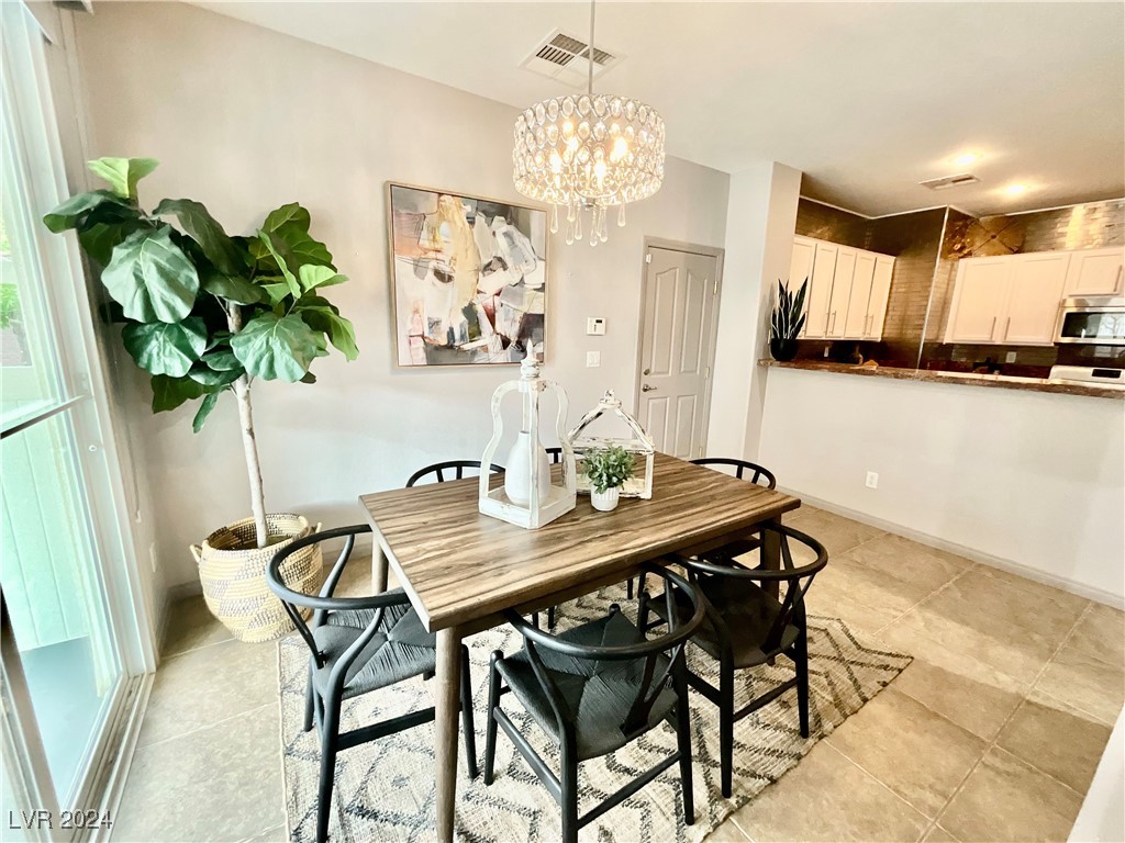 Dining area with a wood table, black chairs, chandelier, and open kitchen.