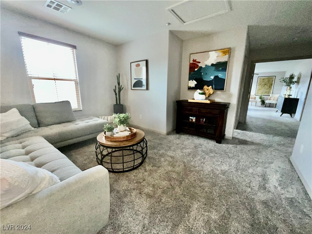 Living room with a gray sectional, round coffee table, and abstract art beside a doorway.