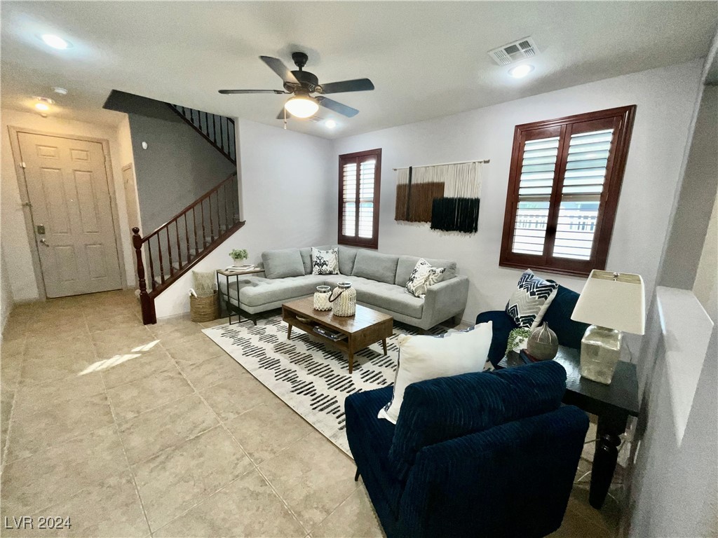 Living room with a gray sectional, navy armchair, patterned rug, and staircase.
