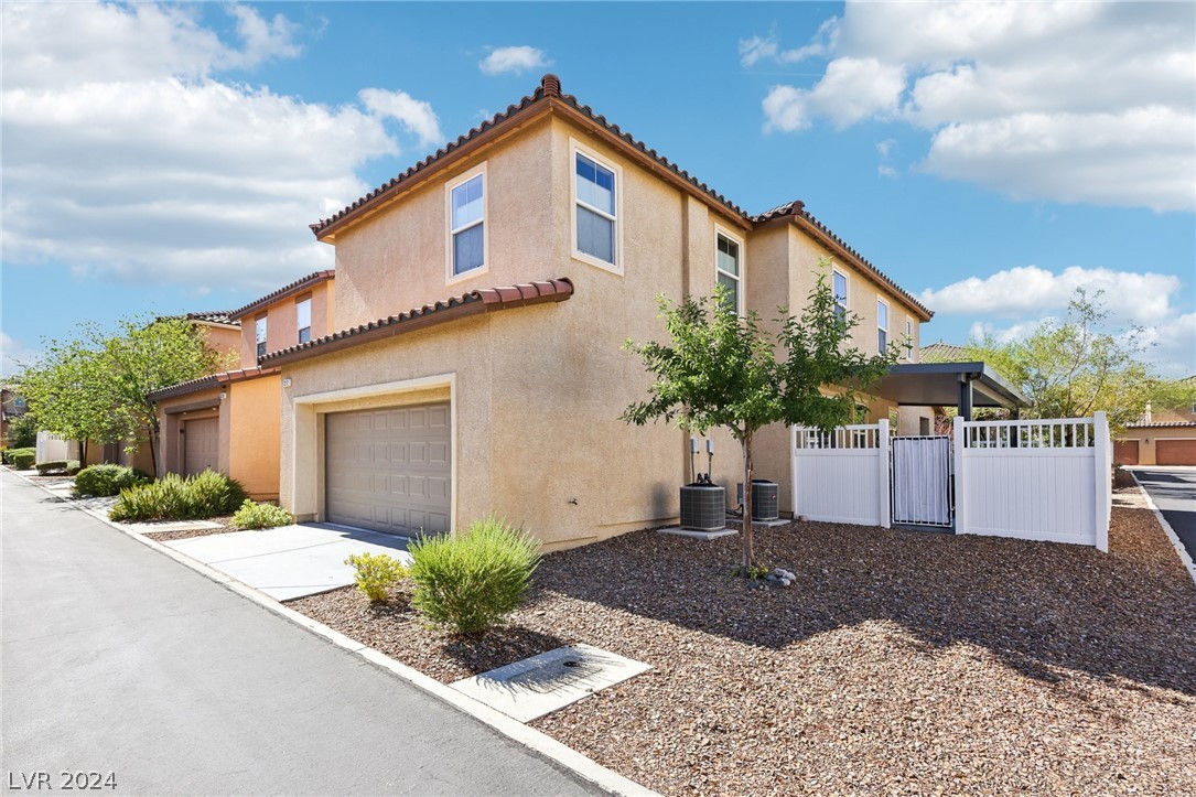 Two-story stucco home with an attached garage and white-fenced side patio.