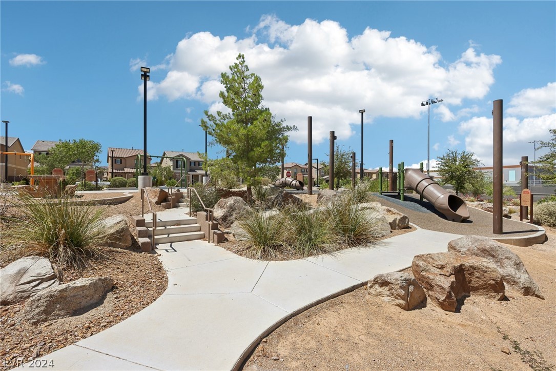 Neighborhood playground with winding paths, desert landscaping, and large play tunnels.