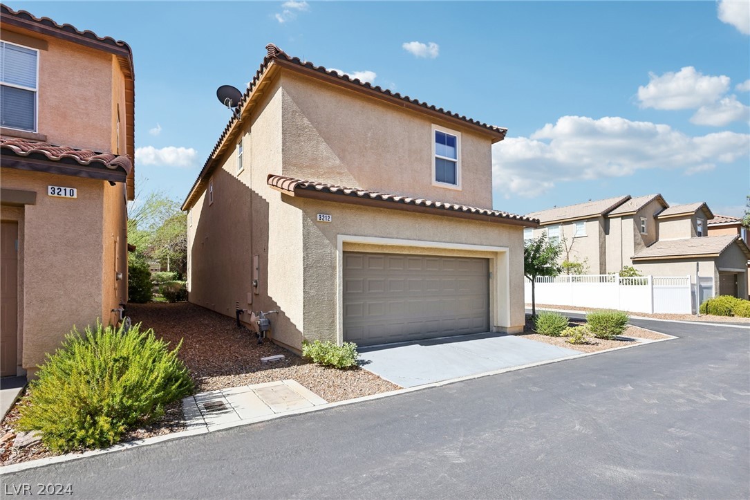 Two-story stucco home with a two-car garage, tiled roof, and desert landscaping.
