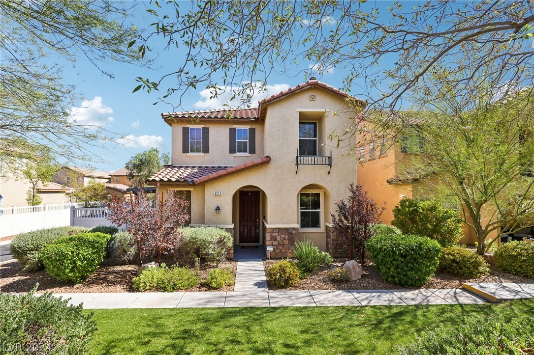 Two-story stucco home with a tiled roof, arched entry, and landscaped front yard.