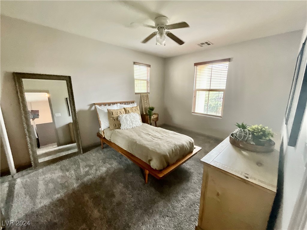 Furnished bedroom with a wooden bed, gray carpet, and large leaning floor mirror.