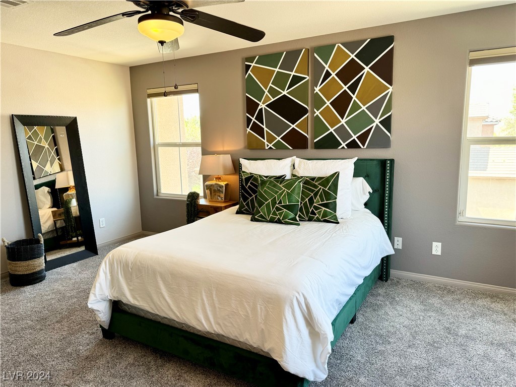 Staged bedroom with a white bed, dark green frame, geometric pillows, and matching wall art.