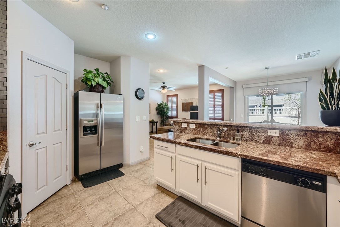 Kitchen with white cabinets, granite counters, stainless appliances, and an open view to the living area.
