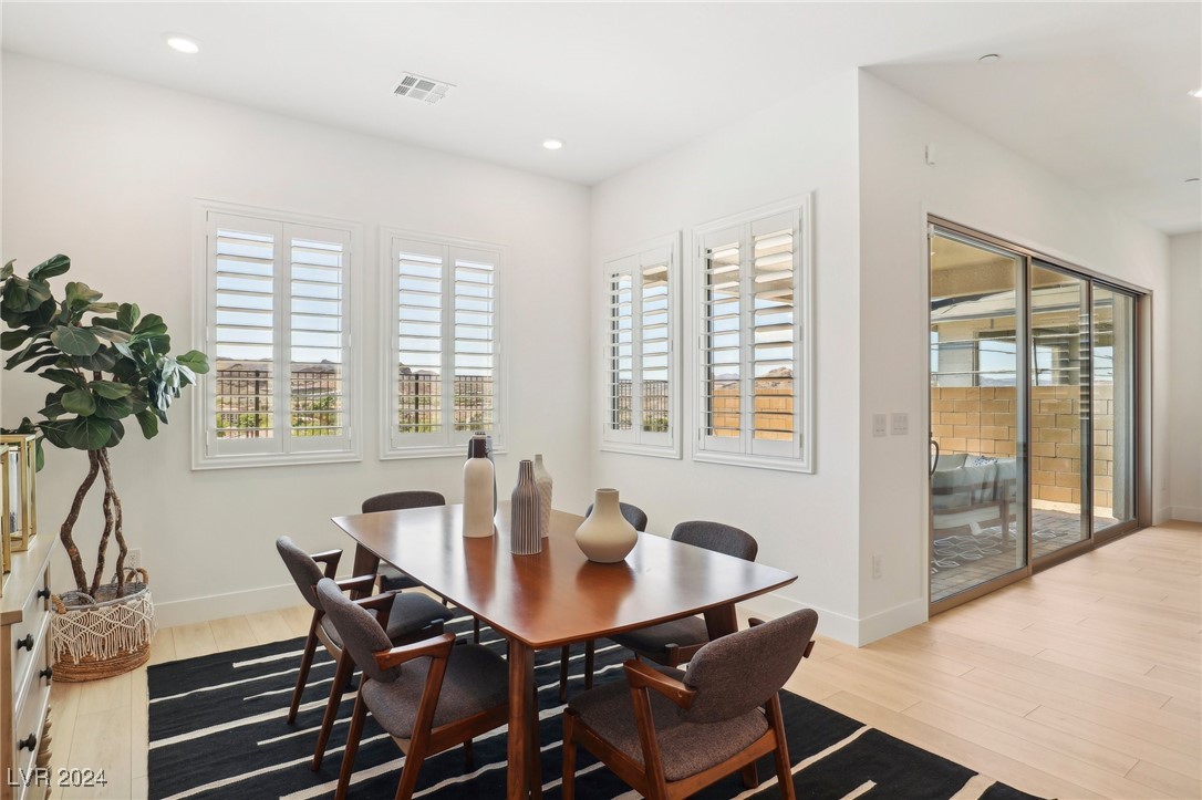Dining area with a wood table, striped rug, plantation shutters, and sliding glass door to a patio.