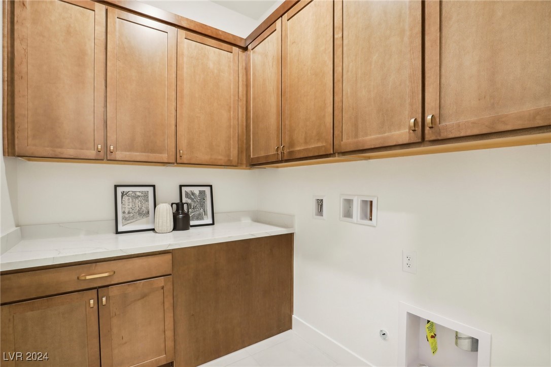 Laundry room with warm wood cabinets, a white countertop, and recessed washer hookups.