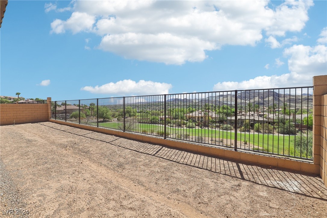 Gravel patio overlooking a green golf course and distant mountains.