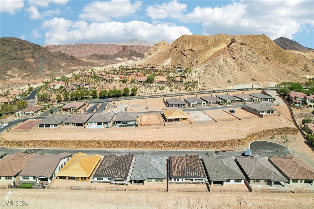 Aerial view of homes and graded lots backed by rugged desert mountains.
