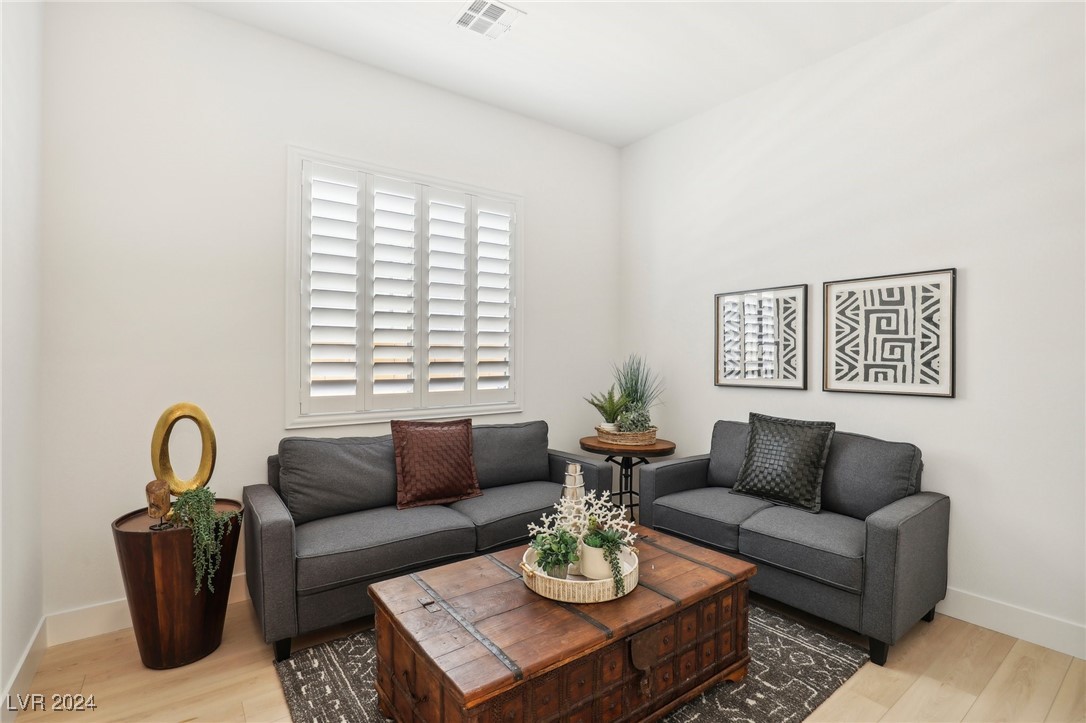 Living room with gray sofas, a wooden trunk coffee table, and white plantation shutters.