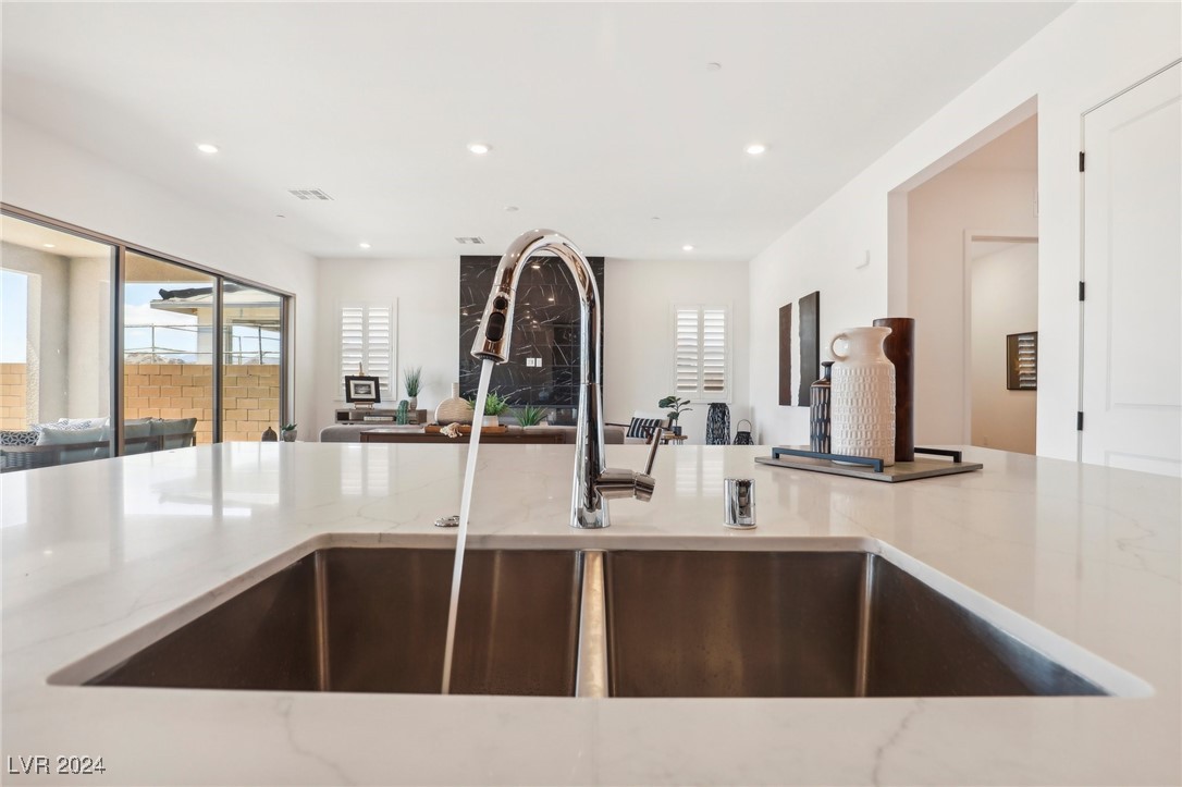 Modern kitchen island with a double-basin sink, chrome faucet, and sliding doors to a covered patio.