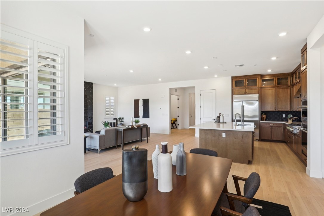 Open-plan kitchen and dining area with a large island, dark wood cabinets, and plantation shutters.