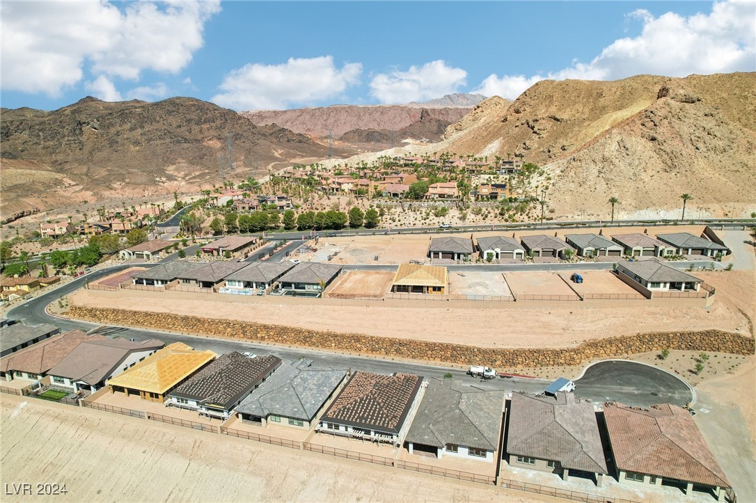 Aerial view of homes and developing lots set against rugged desert mountains.