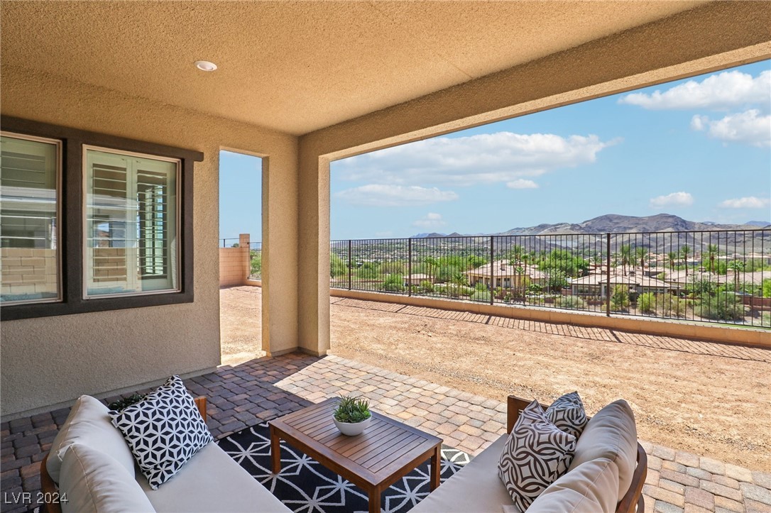 Covered patio with cushioned seating and mountain views beyond the railing.