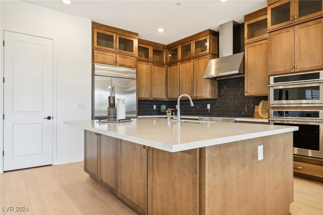 Kitchen with a large white island, warm wood cabinetry, and stainless steel appliances.