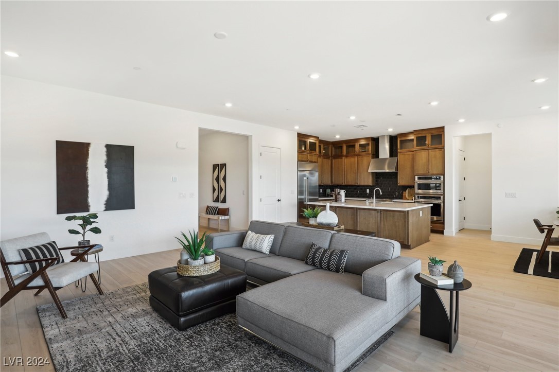 Open-plan living room and kitchen with a gray sectional, wood cabinetry, and a central island.