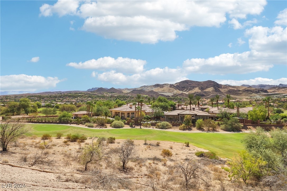 Golf course bordered by homes and palms, with rugged mountains in the distance.