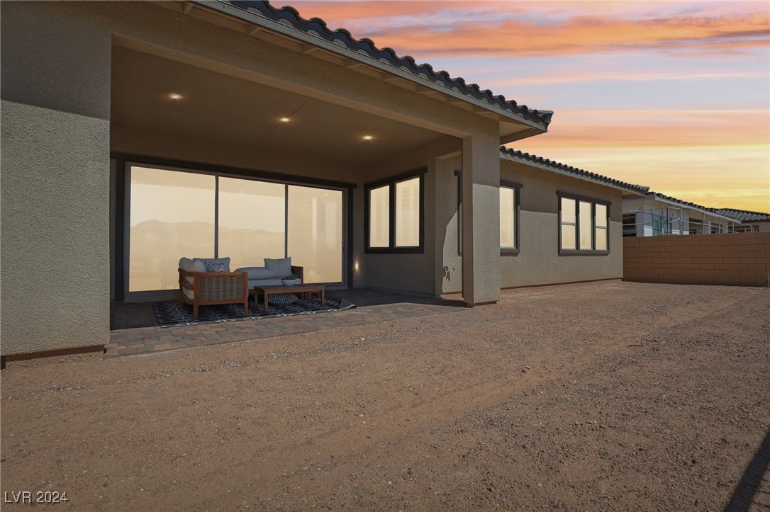 Home’s covered rear patio with sliding glass doors and outdoor seating at sunset.