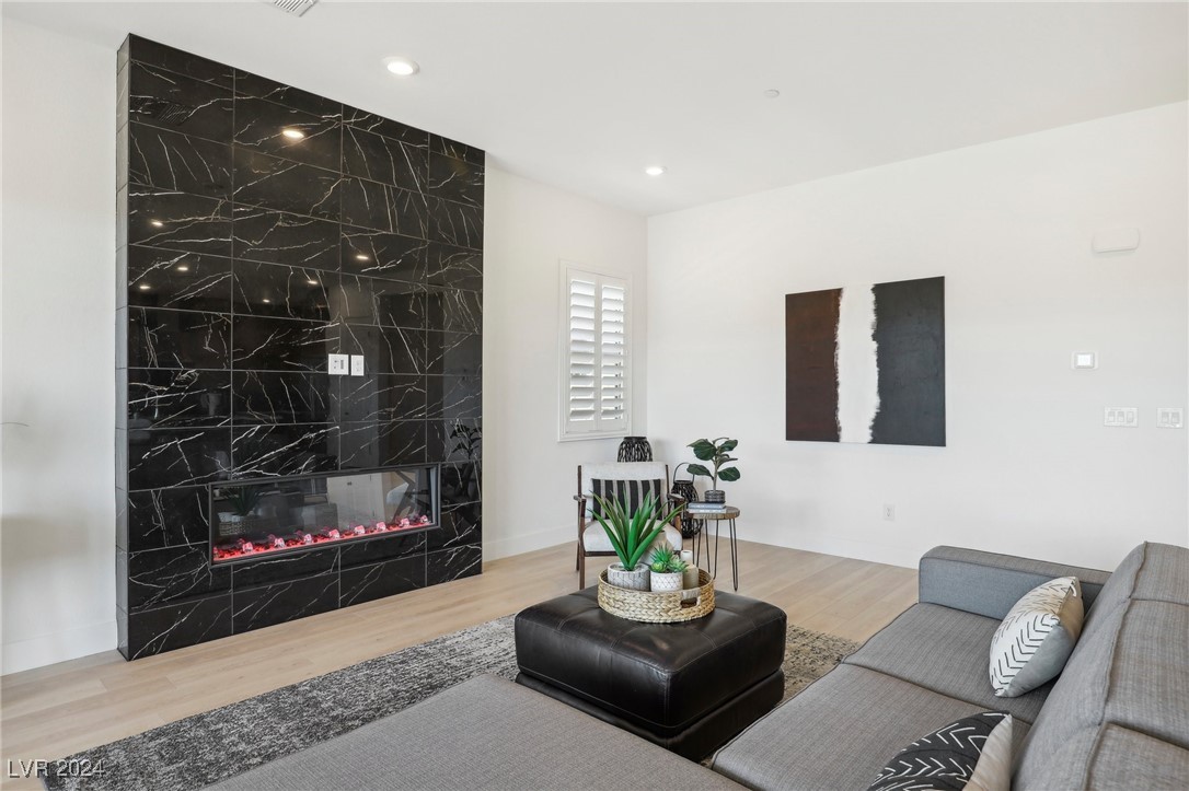 Living room with a black marble-look fireplace wall, gray sectional, and black leather ottoman.