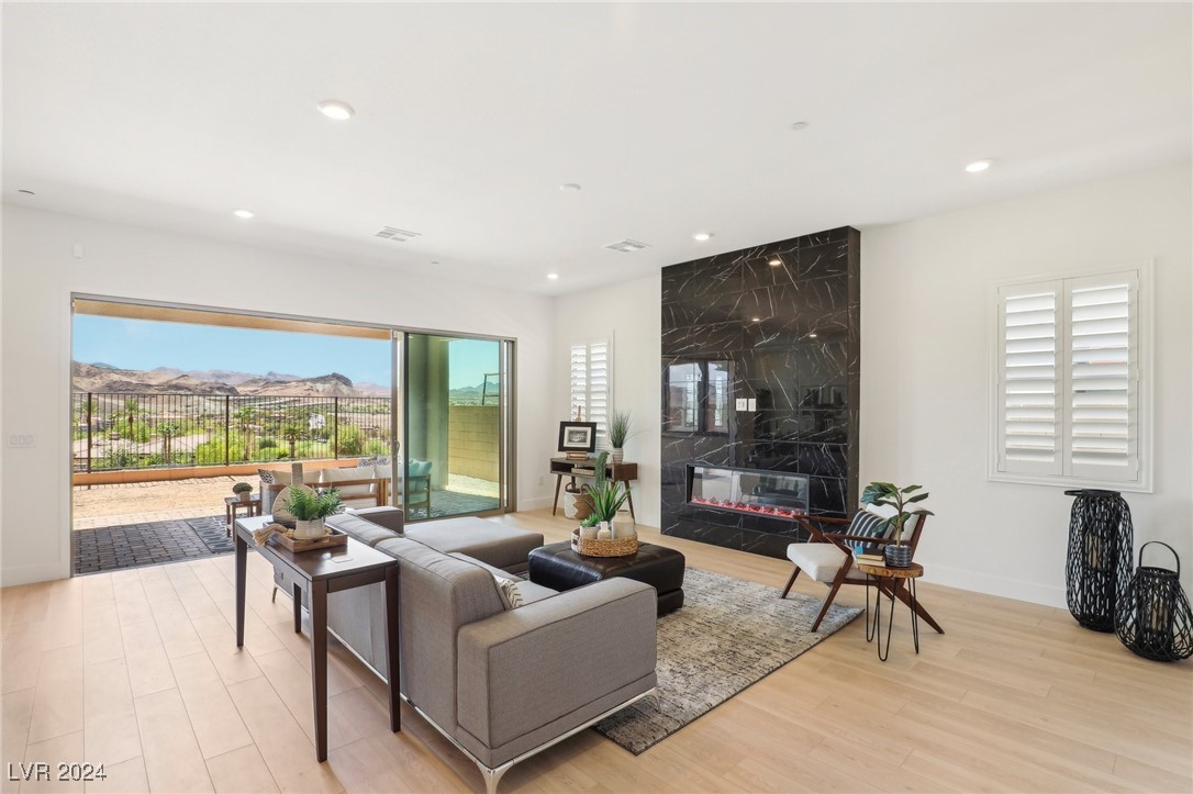 Living room with a gray sectional, black marble fireplace wall, and mountain views through open sliding doors.