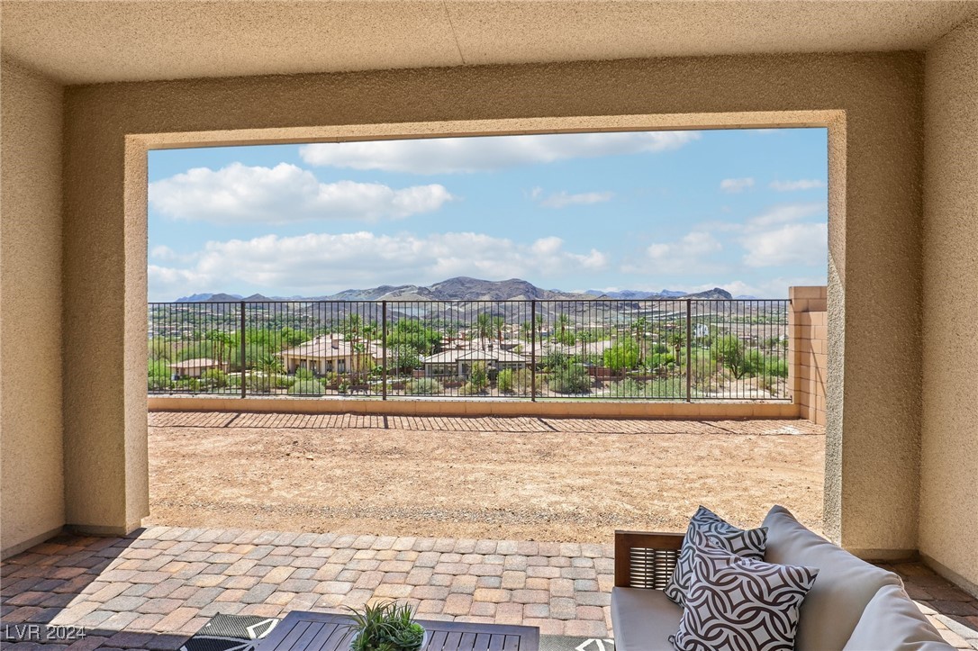 Covered patio with cushioned seating and a broad view of distant mountains.