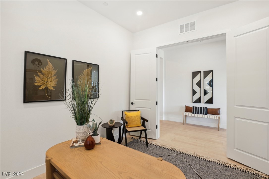 Furnished entryway with a wood console table, botanical artwork, and yellow-cushioned chair.