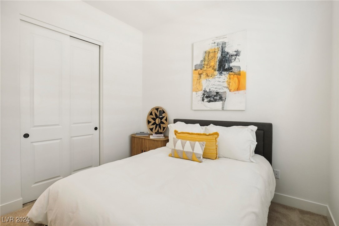 Staged bedroom with a white bed, yellow accent pillows, and abstract wall art.