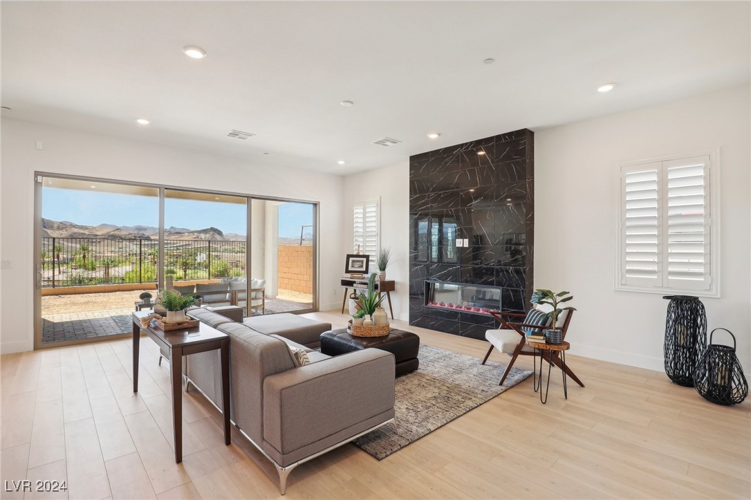 Living room with a gray sectional, black marble fireplace, and sliding doors overlooking a mountain view.