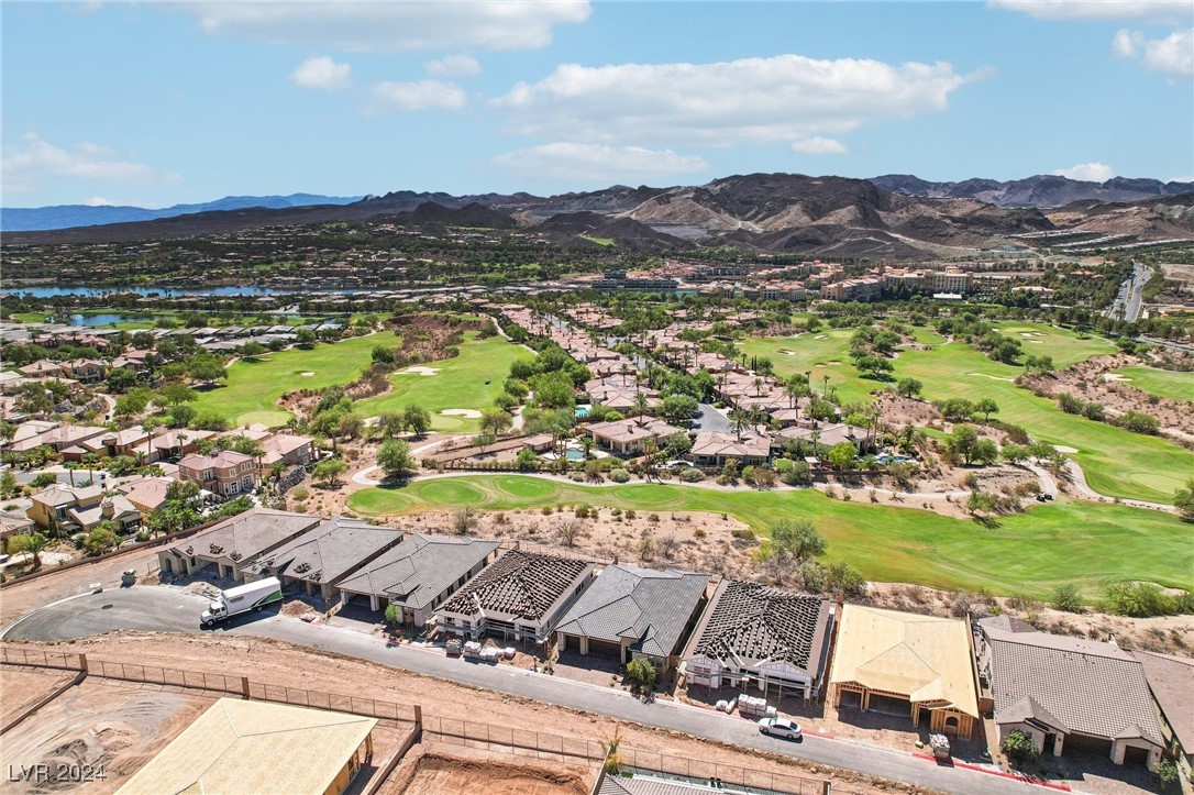 Aerial view of homes under construction beside a golf course, with mountains in the distance.