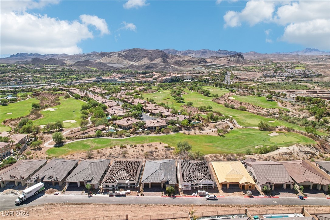 Aerial view of homes beside a golf course, with mountains in the distance.