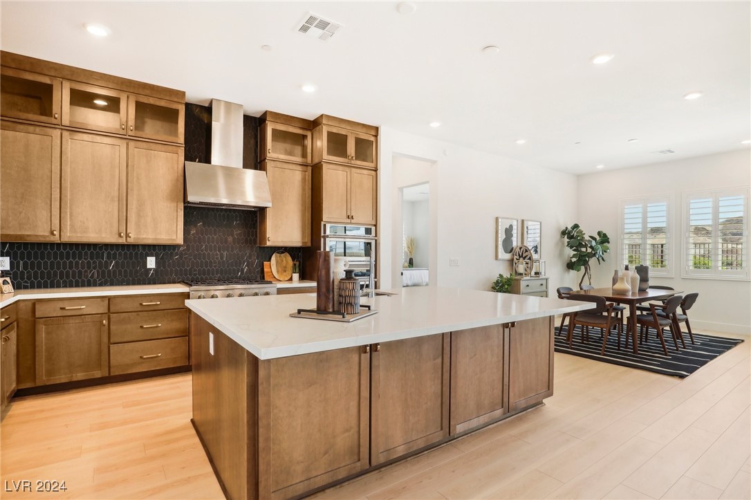 Kitchen with a large white island, warm wood cabinets, and an adjacent dining area.