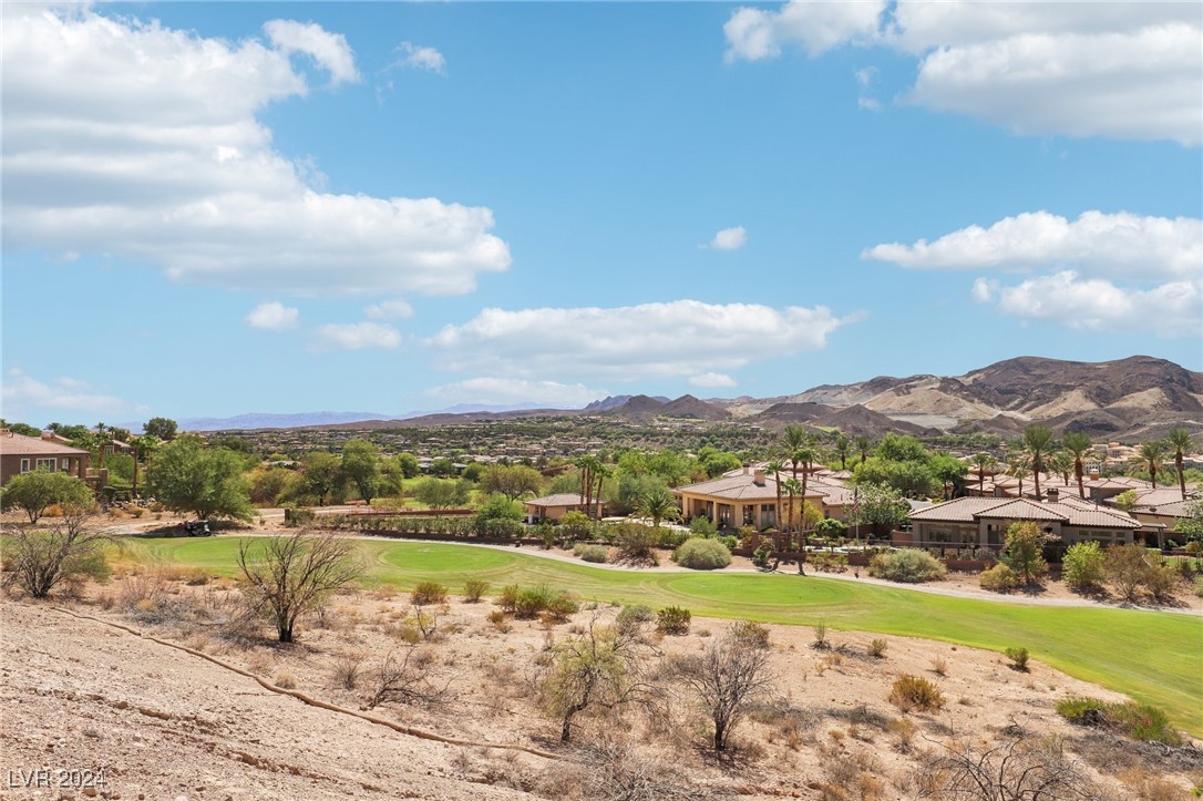 Golf course winding through a desert neighborhood, with homes and mountains beyond.