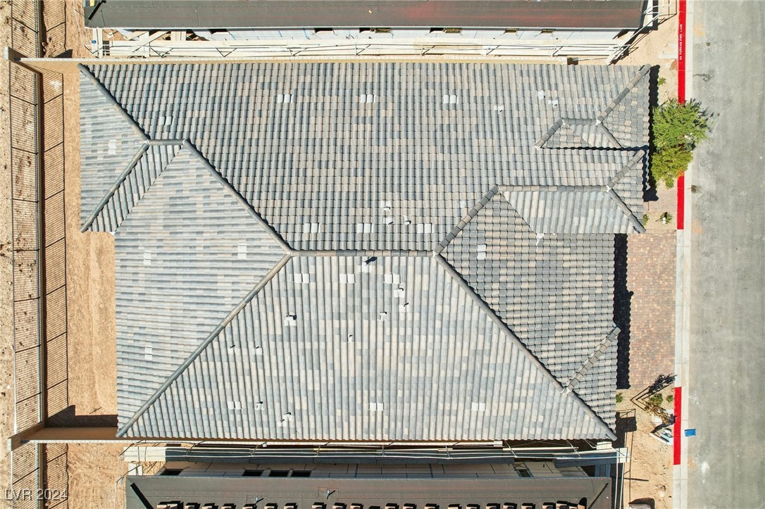 Aerial view of a large gray tiled roof bordered by scaffolding and bare ground.