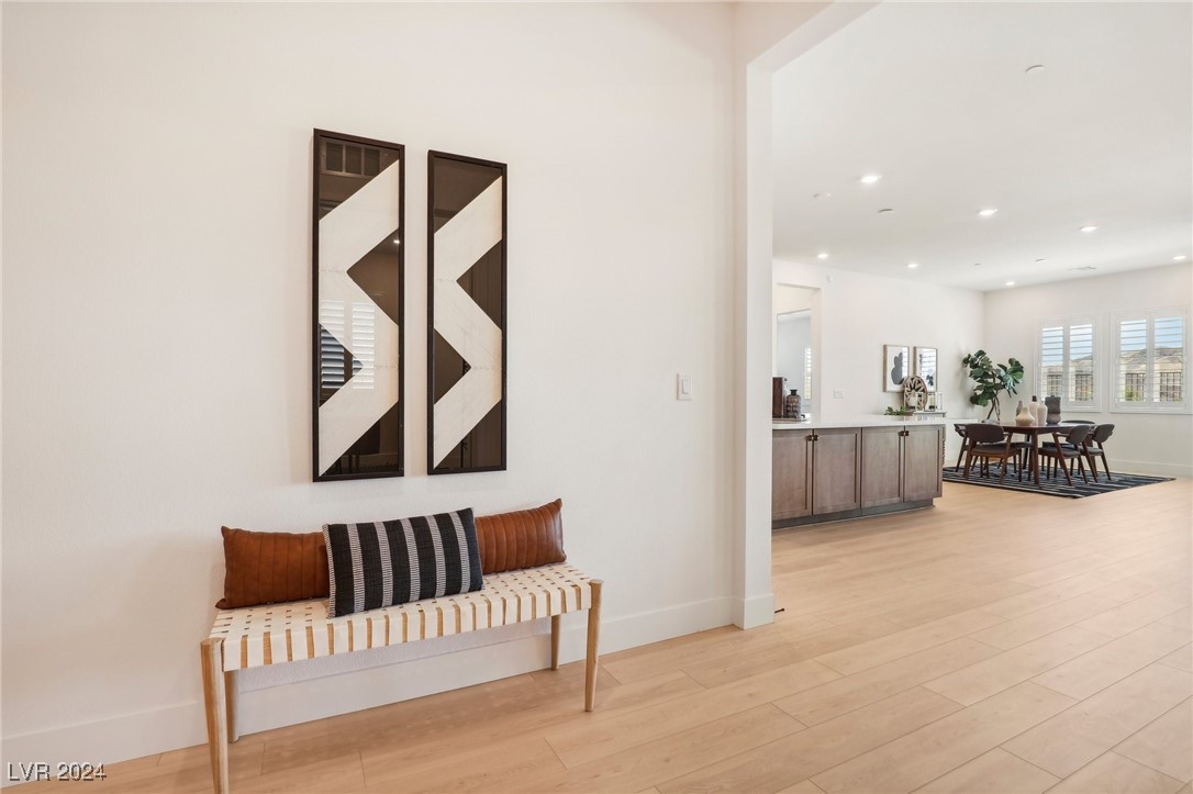 Staged entryway with a striped bench and geometric wall art, opening onto the dining area and kitchen.