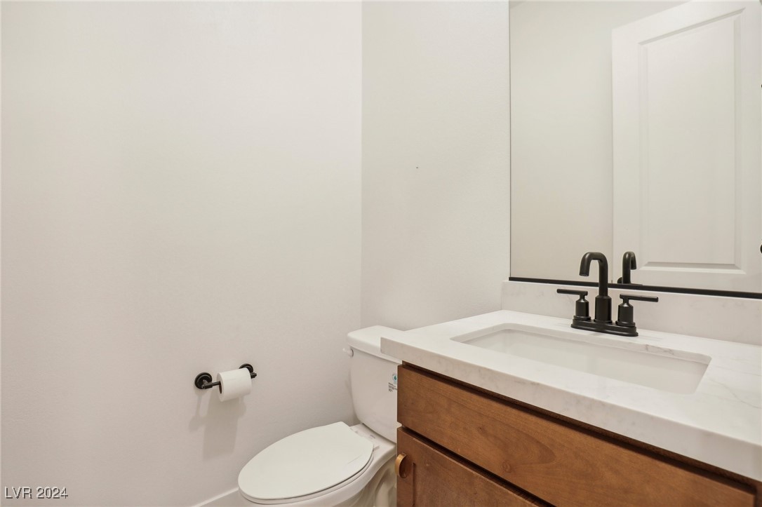 Bathroom with a wood vanity, white sink, black faucet, and toilet.